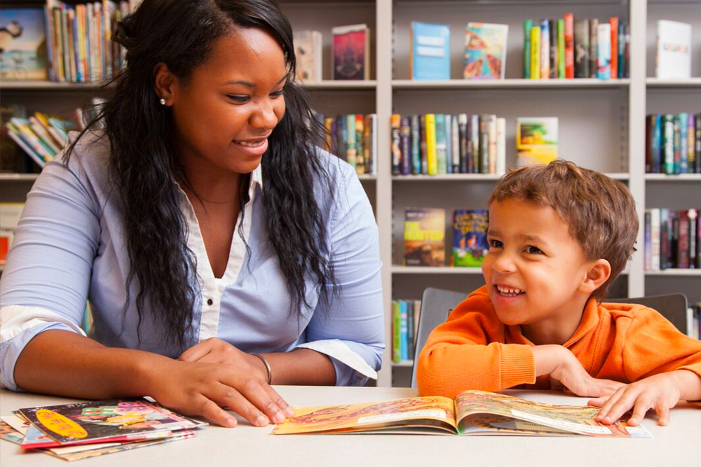 Student teacher reads book with a student