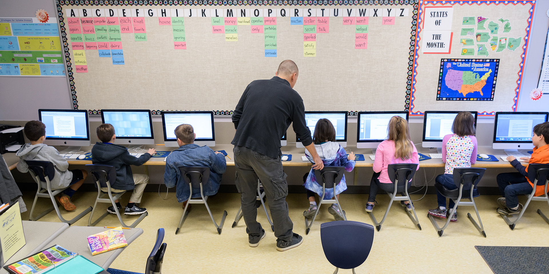 Teacher shows young students how to use computer program