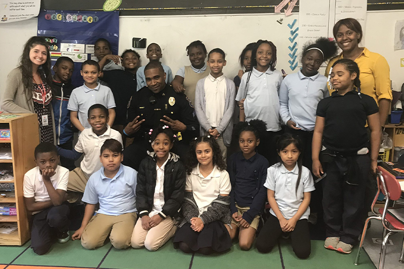 An elementary class at Warner Elementary poses for a group photo with a community police officer